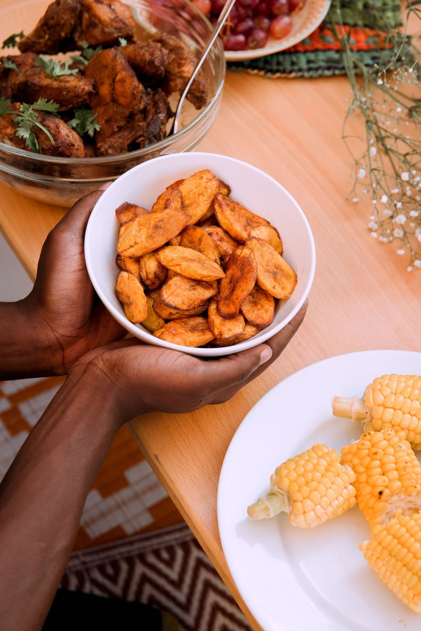 Des plantains frits et du maïs sur une table en bois